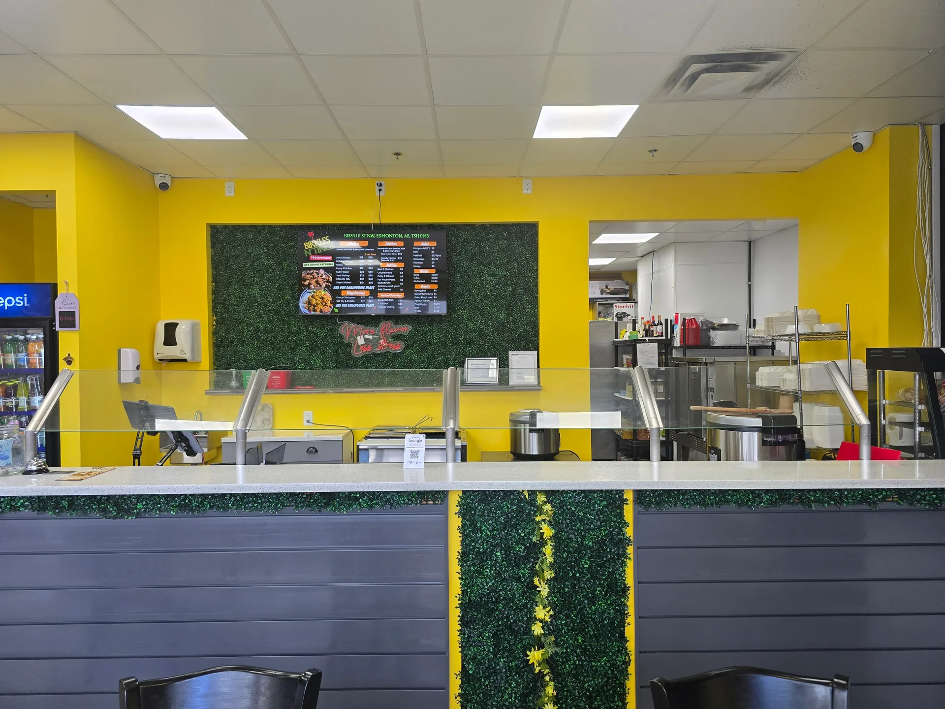 Digital menu board above the order counter at Bikkles N’ Tings Caribbean Eatery in Edmonton, AB