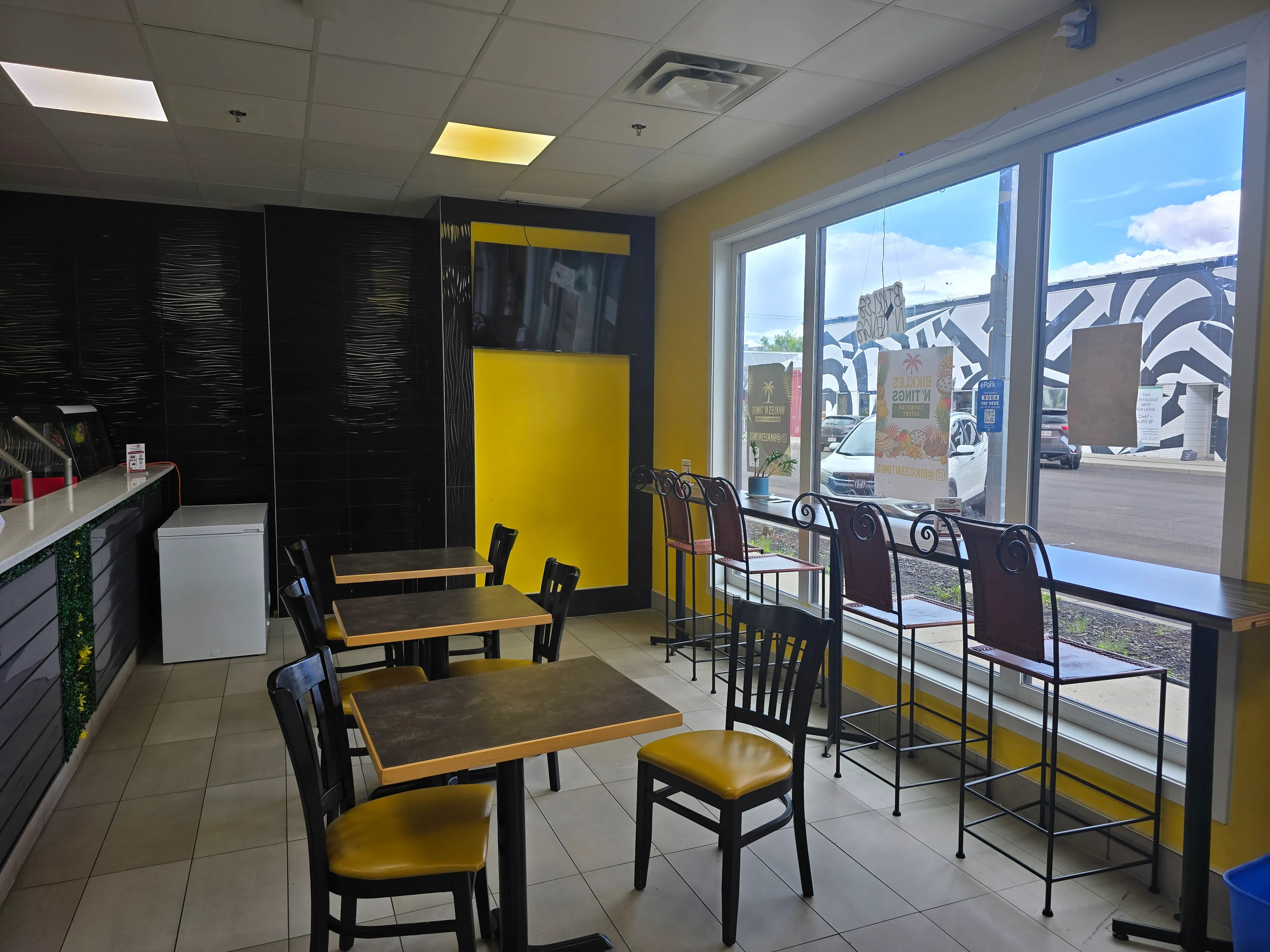 Window-side bar seating in the dining room at Bikkles N’ Tings Caribbean Eatery in Edmonton, AB